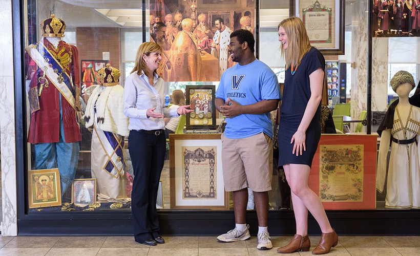 Two students and their professor look at a Russian exhibit in the library.